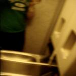 (blurry) taking clothes off in a very cramped airplane lavatory bathroom. (