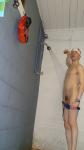 Showering in a white swim cap, removing swim brief