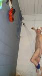 Showering in a white swim cap, removing swim brief