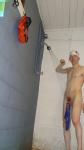 Showering in a white swim cap, with hanging swim brief