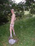 Nude outdoors near a large tree