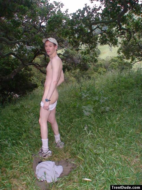 Nude outdoors near a large tree