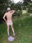 Nude outdoors near a large tree