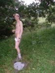 Nude outdoors near a large tree