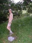 Nude outdoors near a large tree