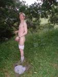 Nude outdoors near a large tree
