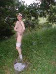 Nude outdoors near a large tree