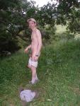 Nude outdoors near a large tree
