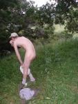 Nude outdoors near a large tree
