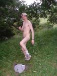 Nude outdoors near a large tree