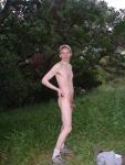 Nude outdoors near a large tree