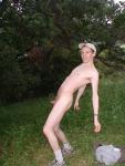 Nude outdoors near a large tree