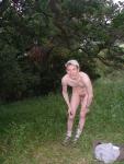 Nude outdoors near a large tree
