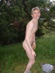 Nude outdoors near a large tree